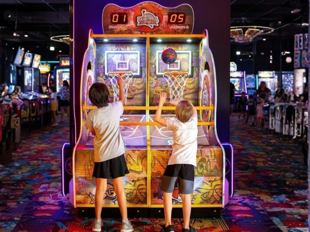 Crianças jogando basquete eletrônico duplo em espaço de jogos